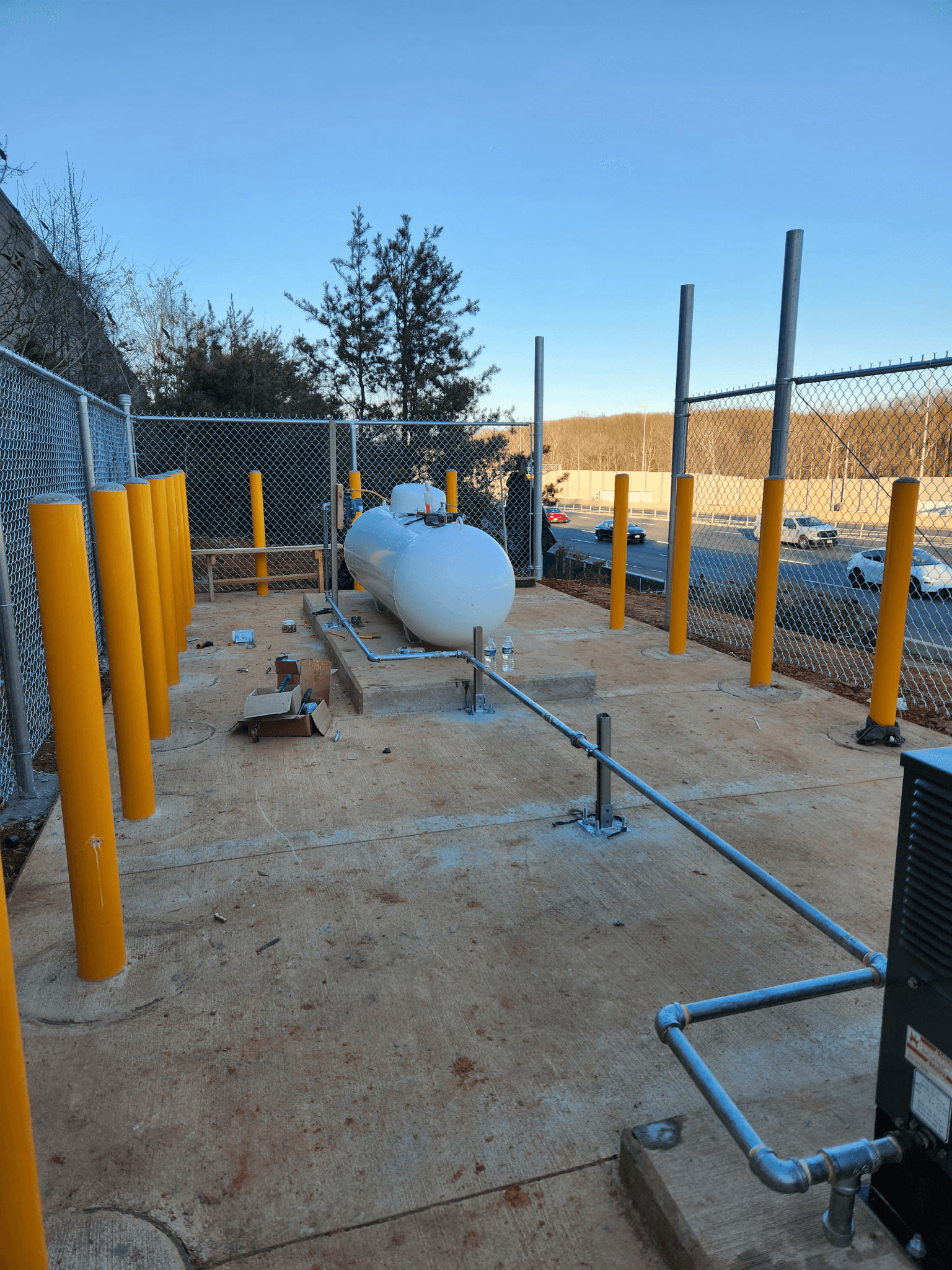 Commercial propane tank installation with above-ground piping and protective yellow bollards